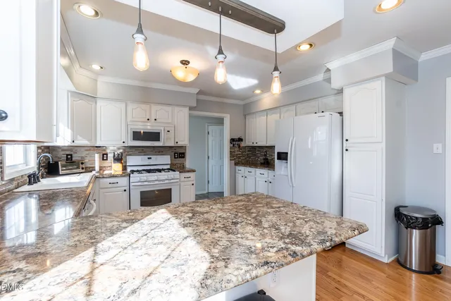 a kitchen with stainless steel appliances kitchen island granite countertop a refrigerator a stove and a sink with granite countertops