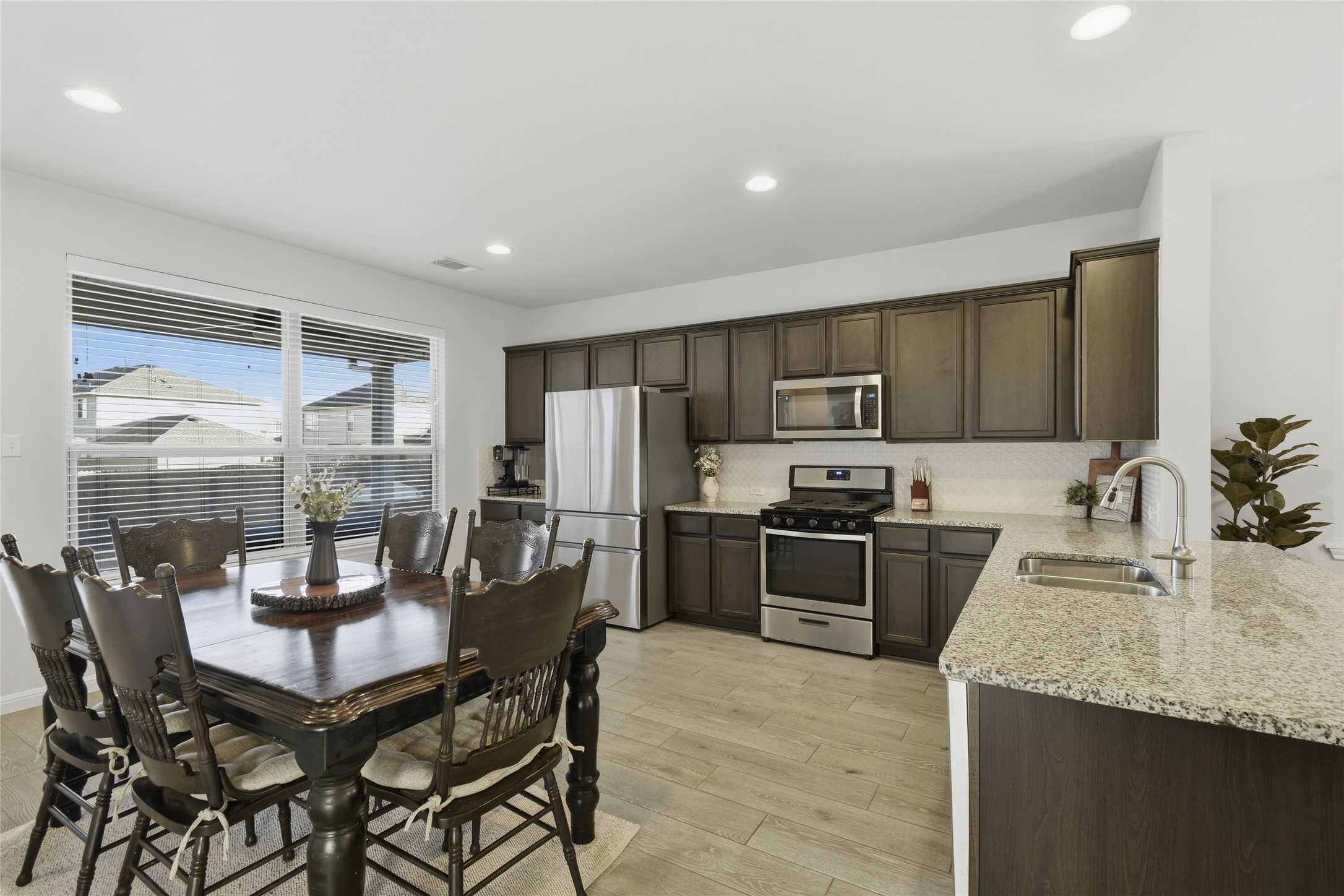8152 Daisy Cutter Crossing Georgetown, TX 78626 - Photo 5 of 23 a kitchen with stainless steel appliances granite countertop a stove top oven a sink a dining table and chairs