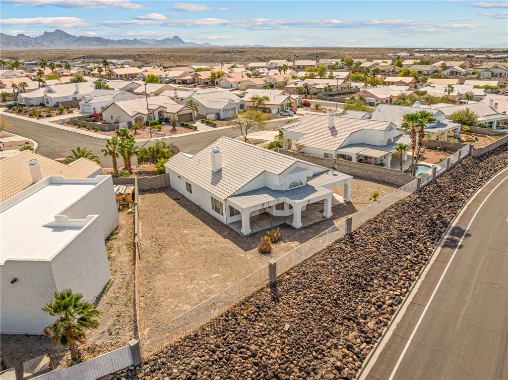 2853 Winchester Road Bullhead City, AZ 86442 - Photo 36 of 40 This property features a single-story residence with a white exterior, a covered patio with columns, and a fenced yard