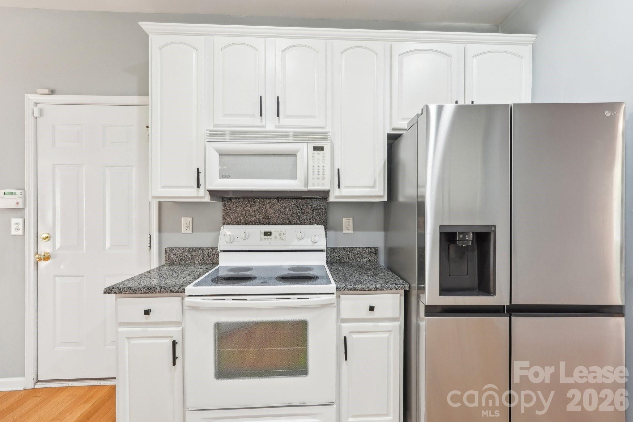 14417 Laurel Tree Lane Huntersville, NC 28078 - Photo 12 of 48 a kitchen with granite countertop white cabinets and refrigerator