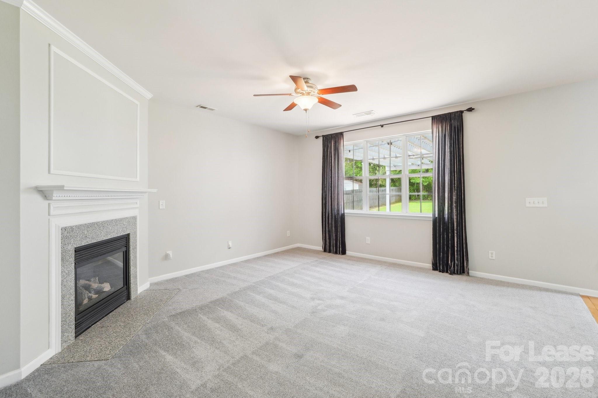 14417 Laurel Tree Lane Huntersville, NC 28078 - Photo 7 of 48 an empty room with windows fireplace and fan