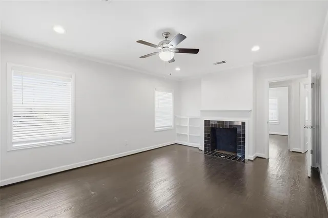 an empty room with wooden floor fireplace and windows