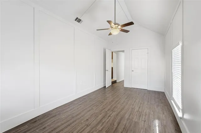 a view of empty room with wooden floor and fan