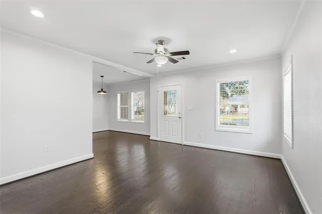 a view of an empty room with a window and wooden floor