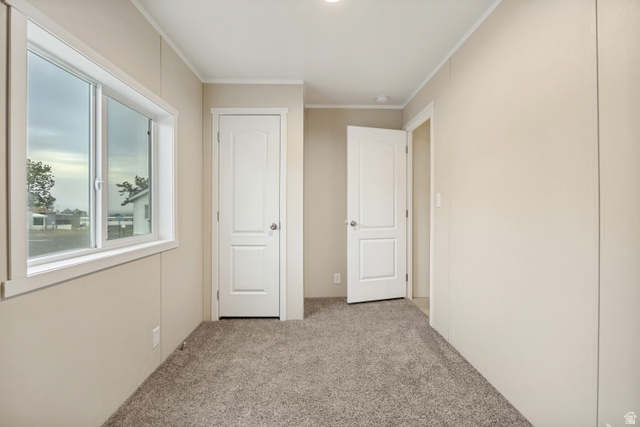 142 Cushing Way Layton, UT 84041 - Photo 8 of 15 Interior space featuring neutral tone wall panels, light brown carpeting, a sliding window with white trim, and two paneled interior doors