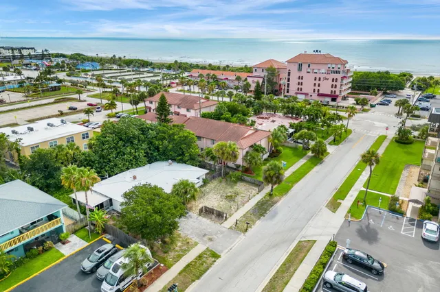an aerial view of a city with lots of residential buildings ocean and mountain view in back