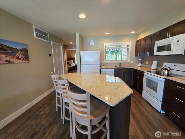 a kitchen with stainless steel appliances granite countertop a kitchen island hardwood floor sink stove dining table and chairs