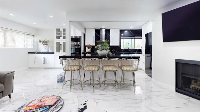 a kitchen with stainless steel appliances kitchen island granite countertop a dining table chairs and granite counter tops