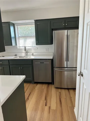 a kitchen with stainless steel appliances a sink a refrigerator and wooden floor