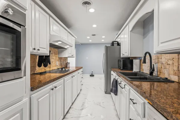 a kitchen with stainless steel appliances granite countertop a sink and dishwasher a stove top oven with wooden floor