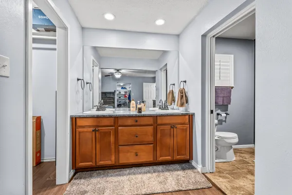 a spacious bathroom with a granite countertop sink a toilet a mirror and shower