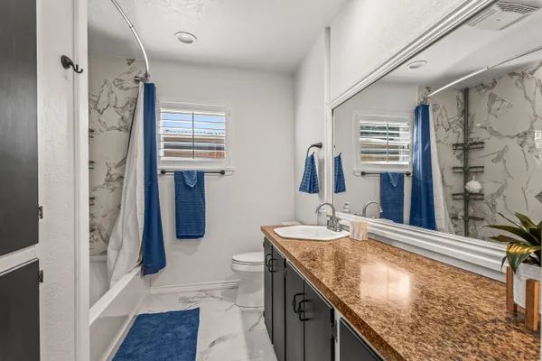 a bathroom with a granite countertop sink a mirror and shower