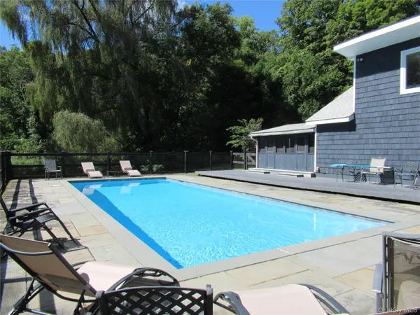 a view of a house with pool and chairs