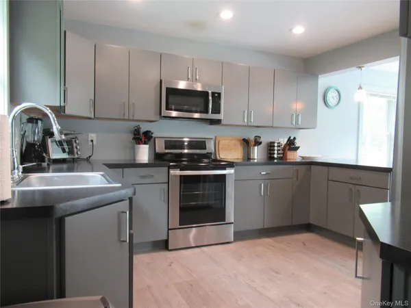 a kitchen with a sink white cabinets and stainless steel appliances