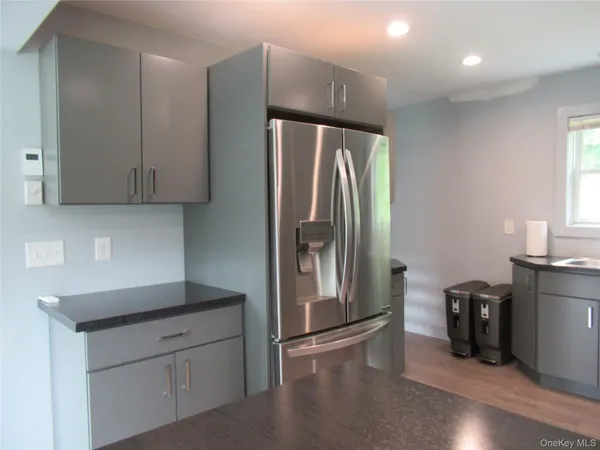 a kitchen with stainless steel appliances granite countertop a refrigerator a sink and a stove with wooden floor