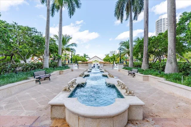 a view of a backyard with a fountain plants and palm tree