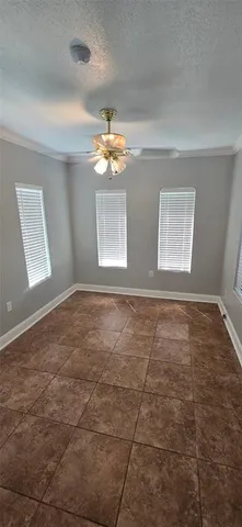 an empty room with windows and chandelier fan