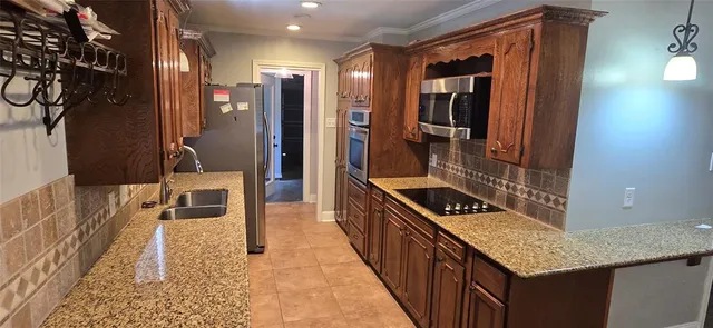 a hallway with a large kitchen island white cabinets and stainless steel appliances