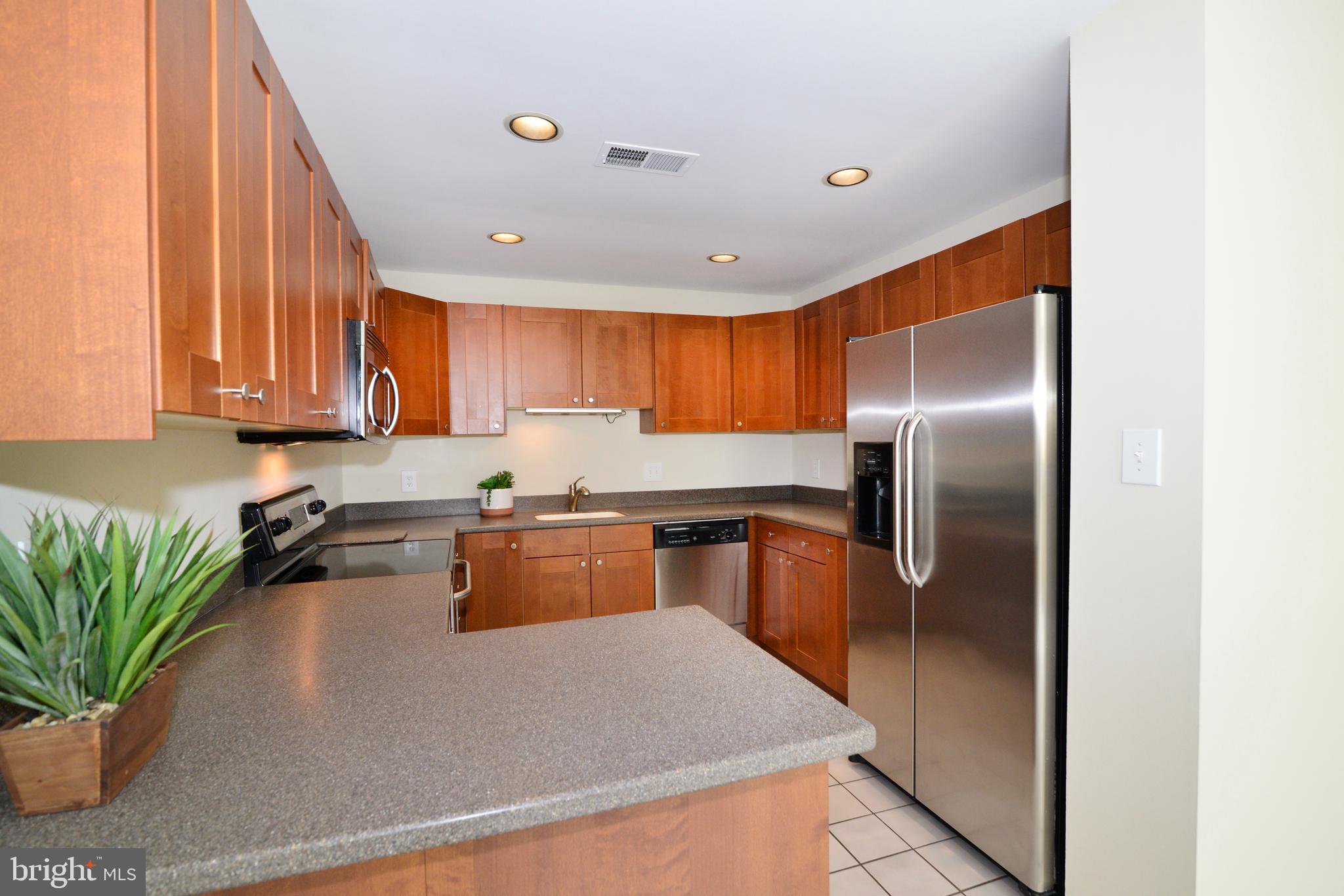 11013 Thrush Ridge Road Reston, VA 20191 - Photo 5 of 38 a kitchen with stainless steel appliances granite countertop a refrigerator a sink a stove a microwave oven with wooden cabinets