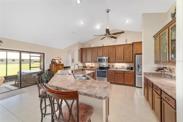 a kitchen with stainless steel appliances kitchen island granite countertop a stove a refrigerator a oven a sink with a dining table and chairs with wooden floor