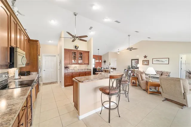 a very nice looking open dining room with kitchen island stainless steel appliances a stove a refrigerator a sink dishwasher a dining table and chairs with wooden floor