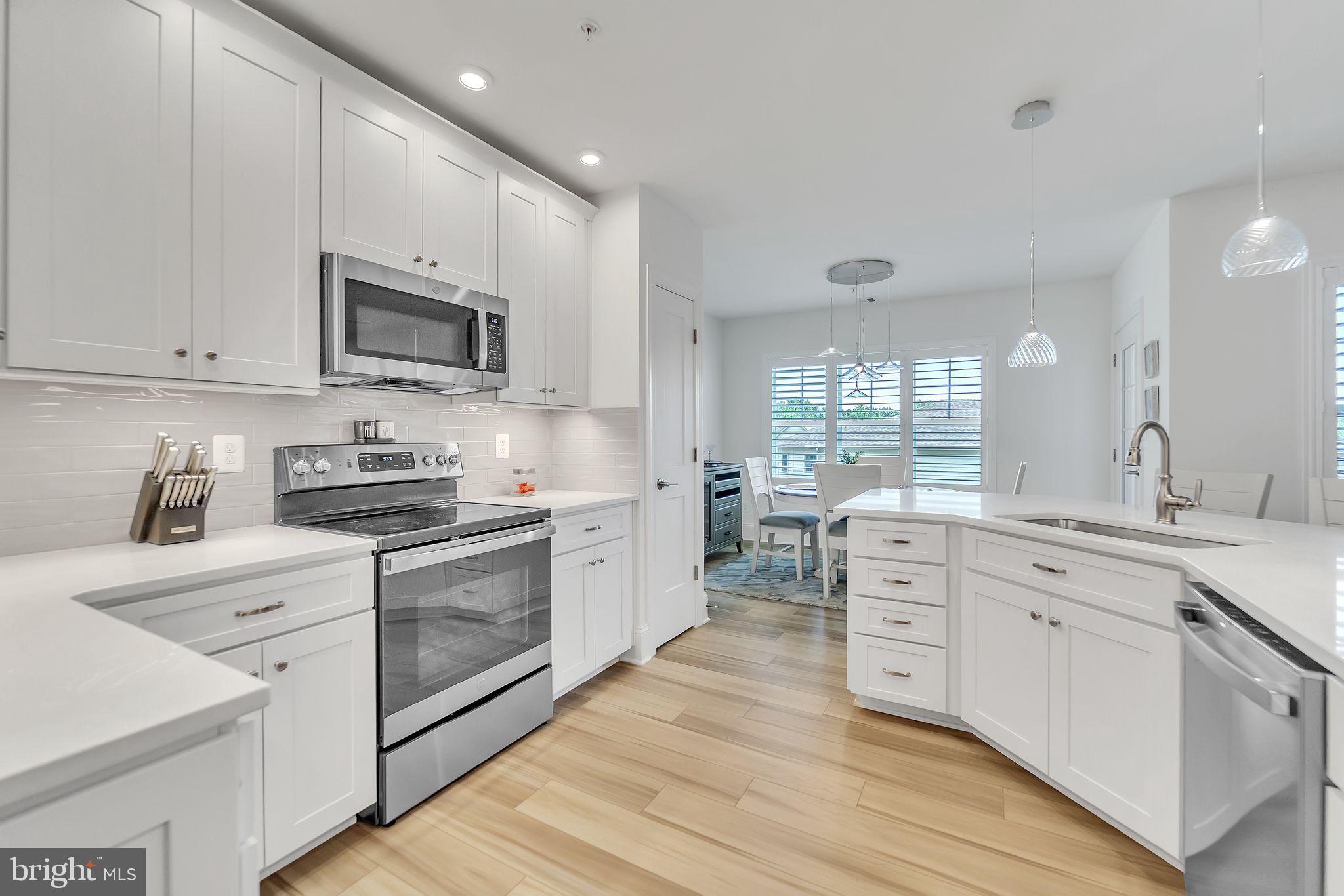 1414 Burke Road, Unit 201 Middle River, MD 21220 - Photo 13 of 35 a kitchen with stainless steel appliances white cabinets a sink a stove a microwave and wooden floors