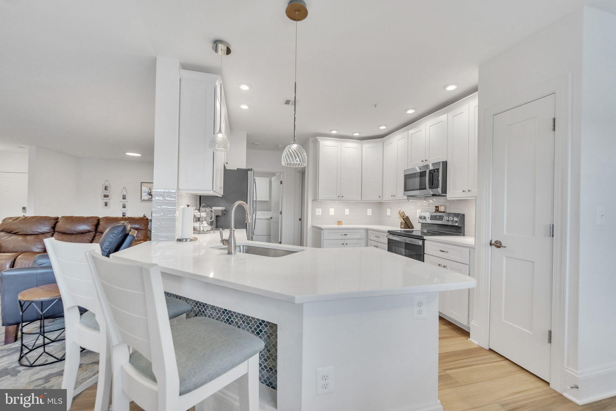 1414 Burke Road, Unit 201 Middle River, MD 21220 - Photo 16 of 35 a kitchen with stainless steel appliances kitchen island granite countertop a table chairs sink and cabinets