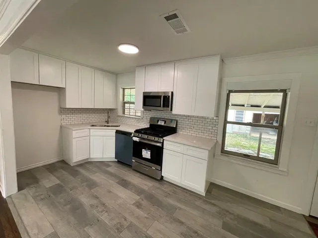 a kitchen with granite countertop white cabinets and black stainless steel appliances