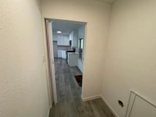 a view of a hallway with wooden floor and a bathroom