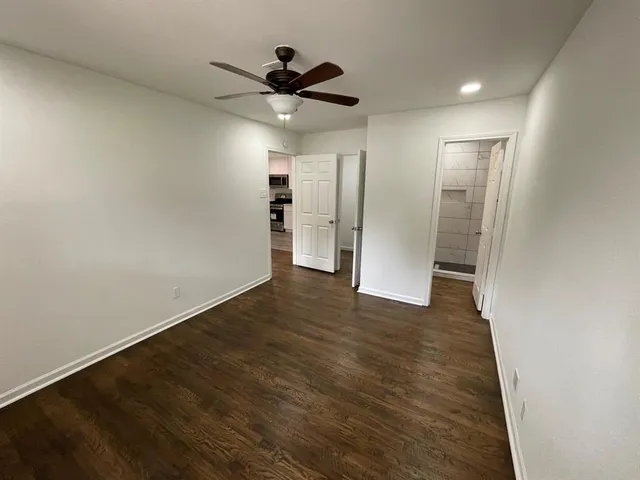 a view of empty room with wooden floor and ceiling fan
