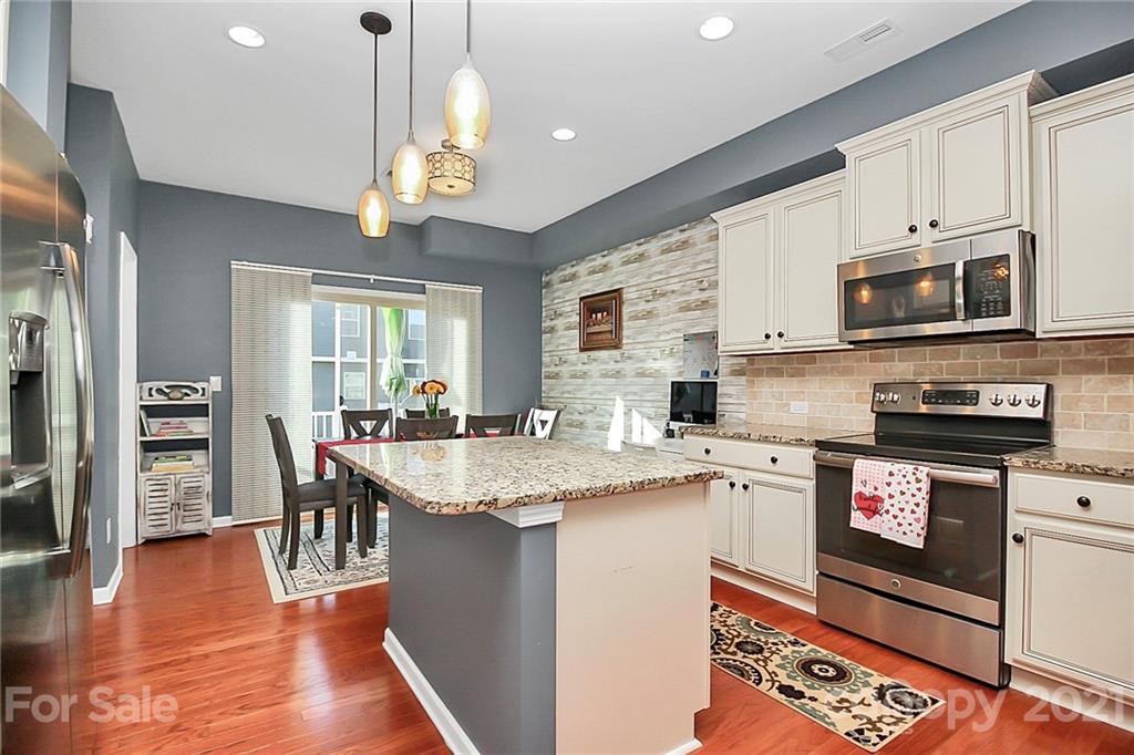110 Layla Drive Tega Cay, SC 29708 - Photo 14 of 35 a kitchen with stainless steel appliances granite countertop a stove top oven a sink dishwasher and a dining table with wooden floor