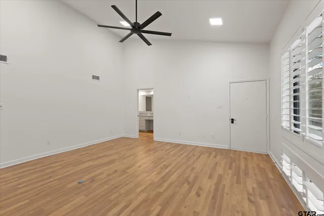 a view of an empty room with a window and wooden floor