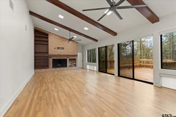 a view of an empty room with a fireplace and a ceiling fan
