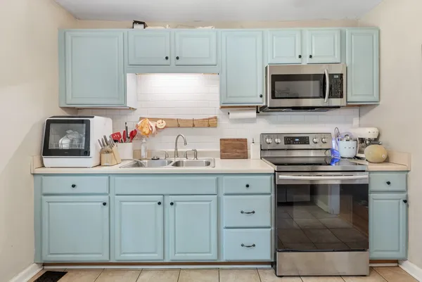 a kitchen with white cabinets and sink