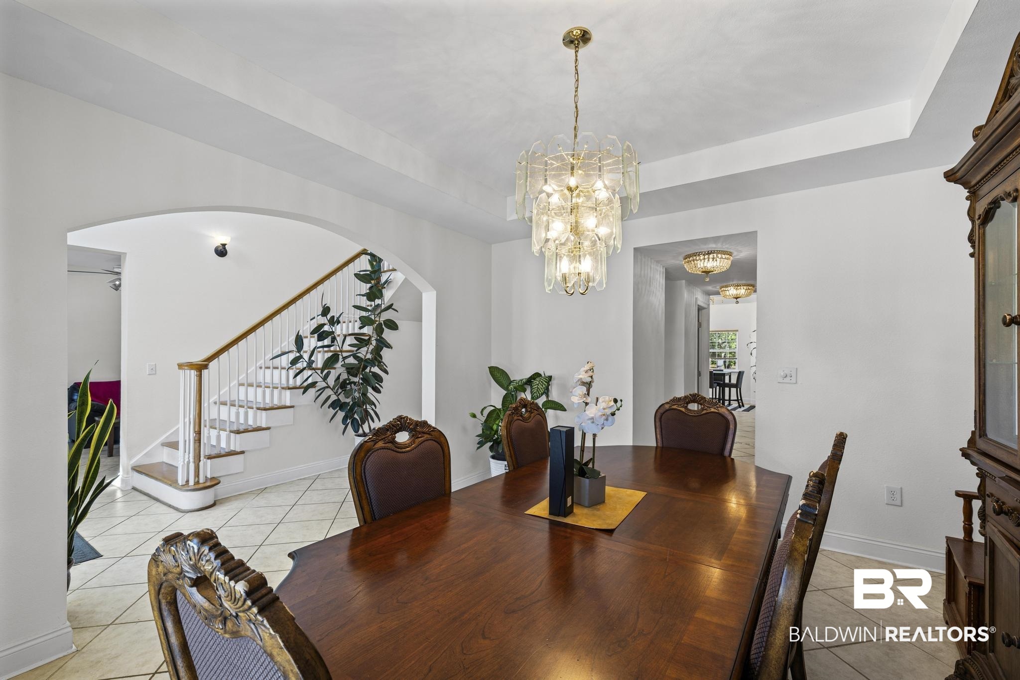 32875 Faircloth Road Lillian, AL 36549 - Photo 19 of 85 Dining space featuring a tray ceiling, light tile patterned flooring, arched walkways, and suspended lighting