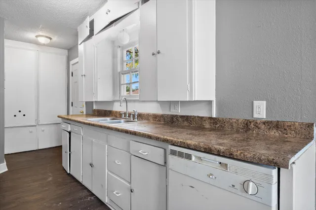 a kitchen with granite countertop white cabinets and a sink