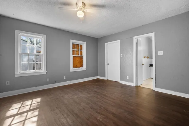 a view of an empty room with wooden floor and a window