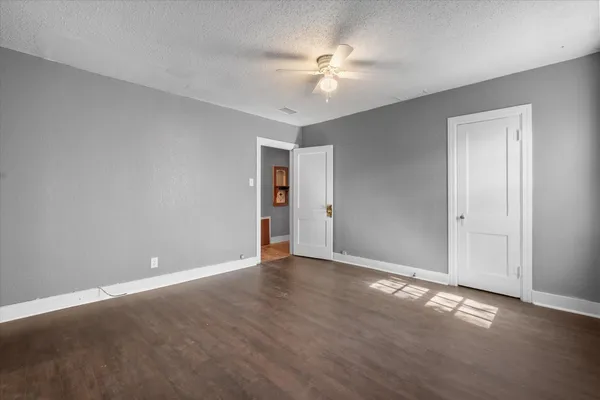 a view of an empty room with chandelier fan