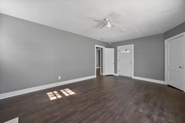 a view of an empty room with window and wooden floor