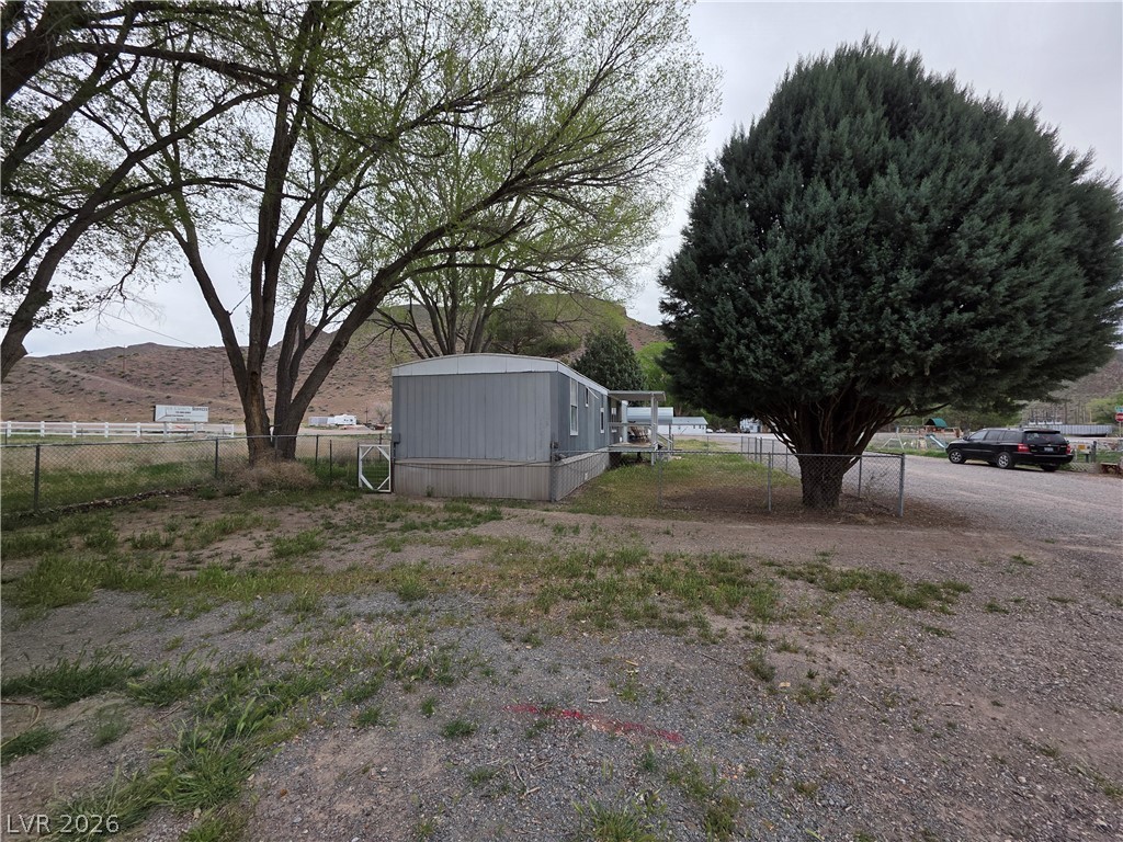 101 Ada Street, Unit 12 Caliente, NV 89008 - Photo 12 of 14 Mature trees and a chain-link fence frame this functional manufactured home.