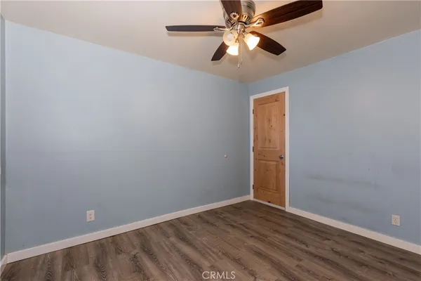 an empty room with wooden floor closet and fan