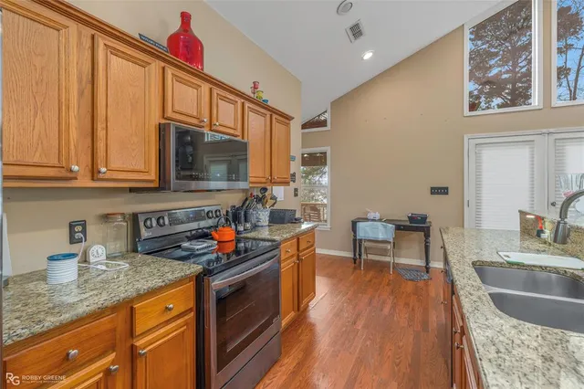 a kitchen with stainless steel appliances granite countertop a stove a sink and a microwave