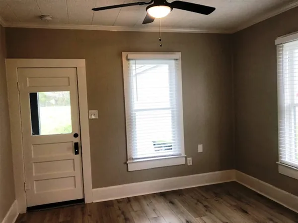 an empty room with wooden floor and windows