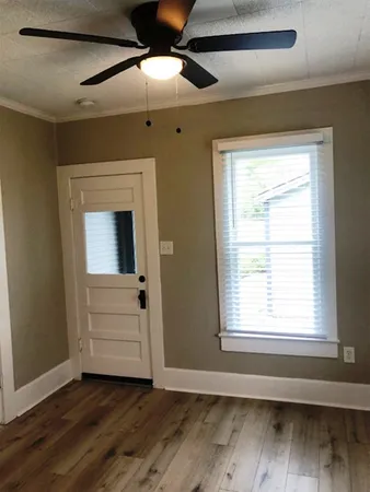 a view of an empty room with wooden floor and a window