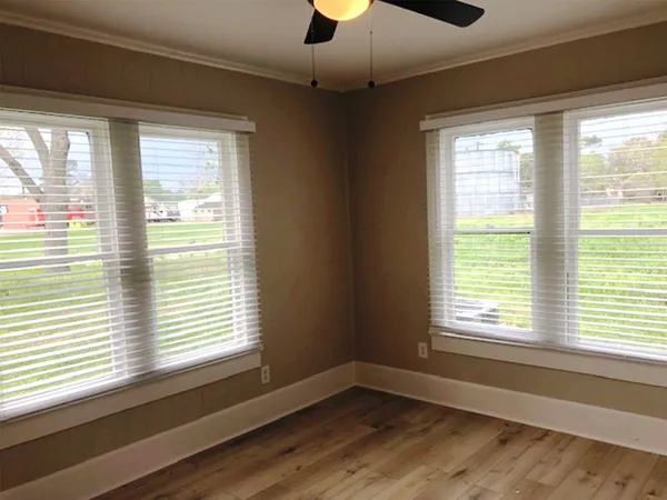 a view of an empty room with a window and wooden floor