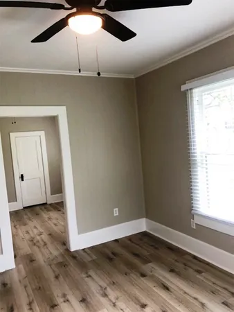 an empty room with wooden floor fan and windows