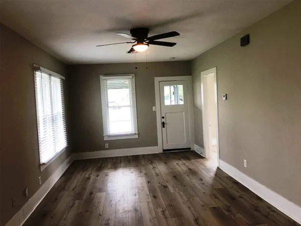 a view of an empty room with wooden floor and a window