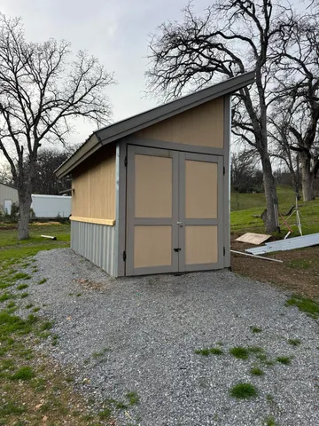 a small barn with a big yard and large trees
