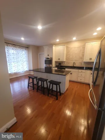 a kitchen with stainless steel appliances granite countertop a stove top oven a dining table and chairs with wooden floor