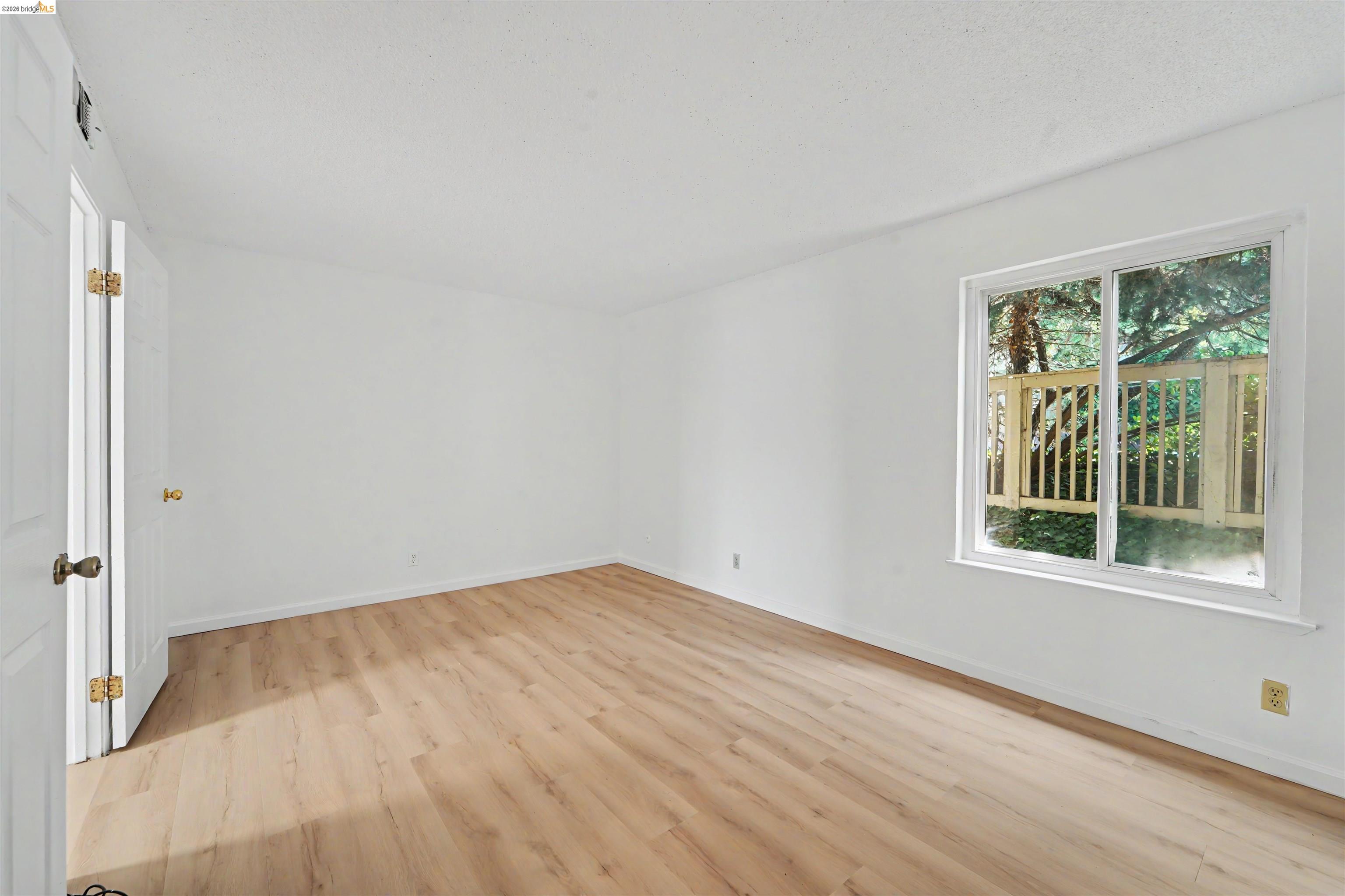 4186 San Pablo Dam Road, Unit A El Sobrante, CA 94803 - Photo 12 of 34 Spacious room with wood-finish flooring, white walls, and a large window